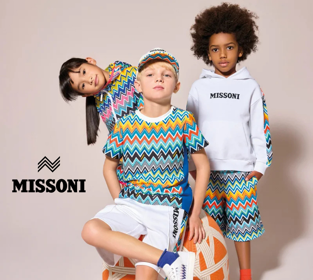 Three children wearing Missoni children's clothing on a plain background